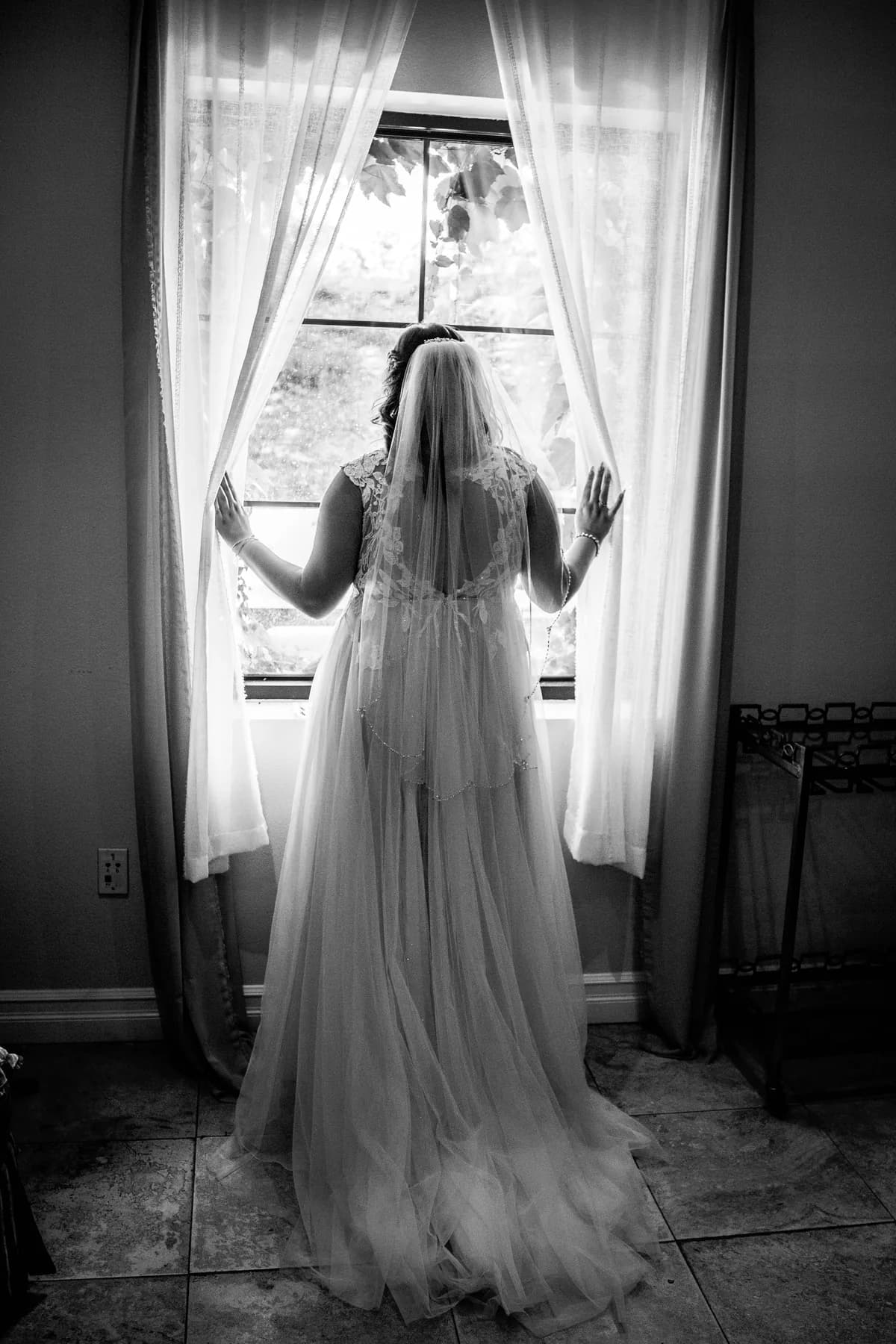 Black-and-white bridal portrait framed by bright window curtains before a Leoness Cellars wedding